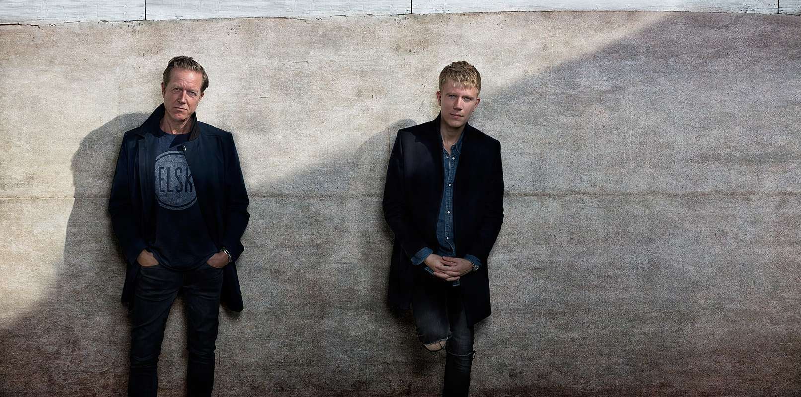 Peter Mygind læner sig op af en mur sammen med sin søn Julius Mygind. Portrætfotograf Christian Krog - www.christiankrog.dk